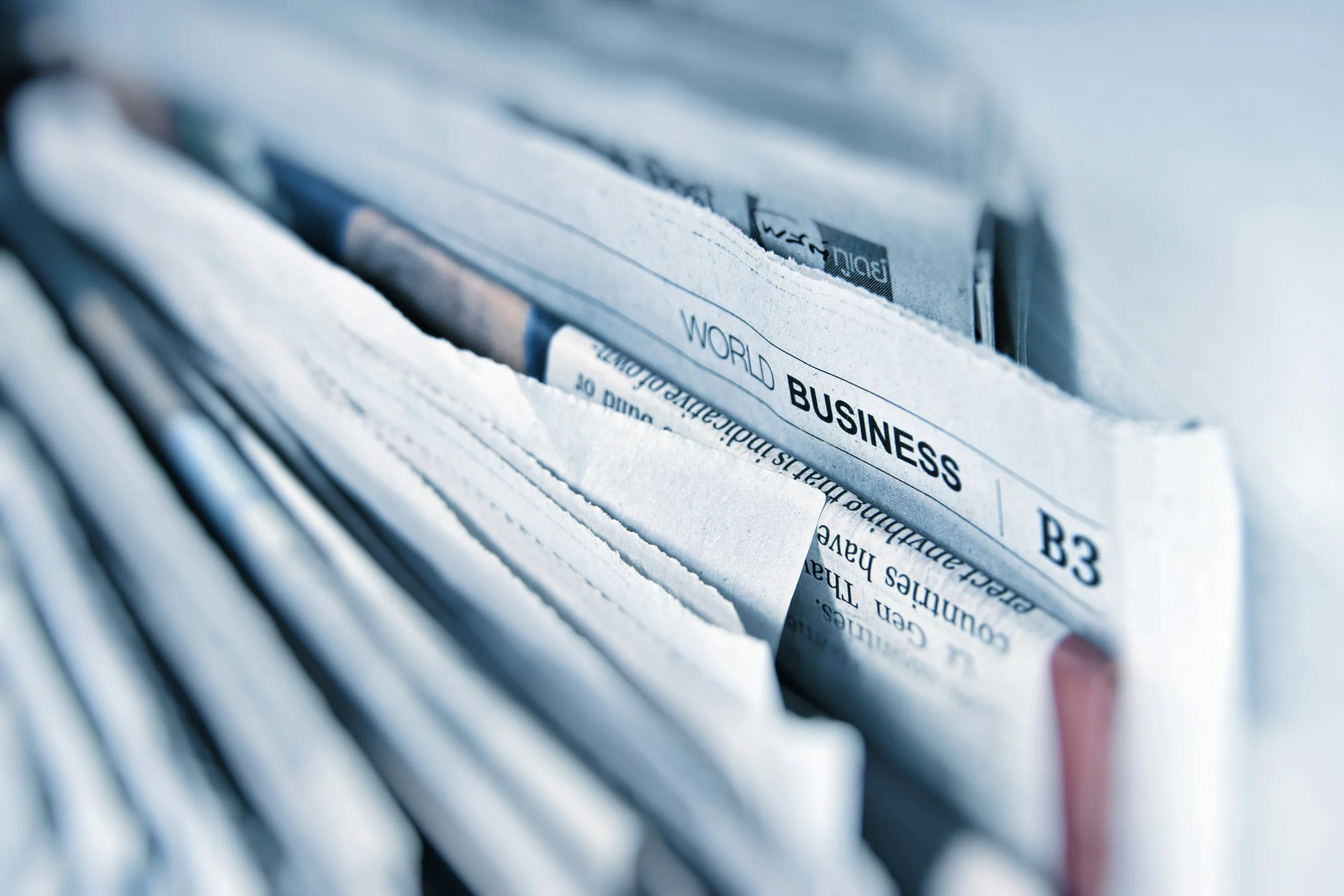 Close-up of folded newspapers, with the “World Business” section in focus.